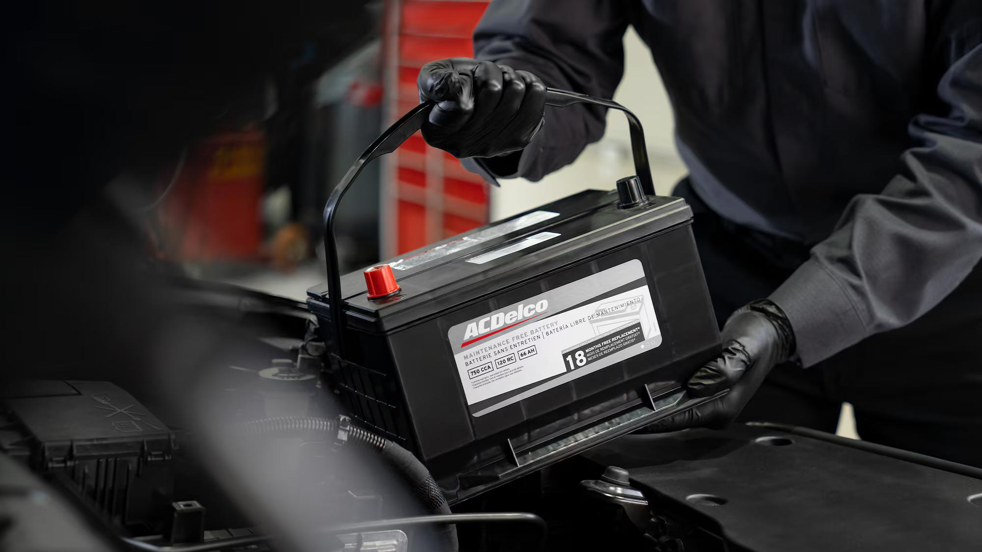 A technician installing a Genuine GM ACDelco battery — the parts that go in your vehicle when GM builds it